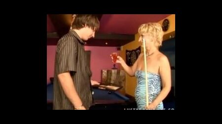 Молодой бармен веселится в комнате для бильярда с пожилой теткой