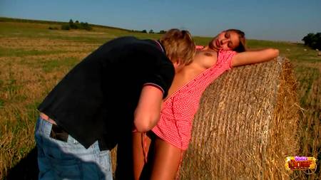 Парень развлекается с подружкой около стога сена